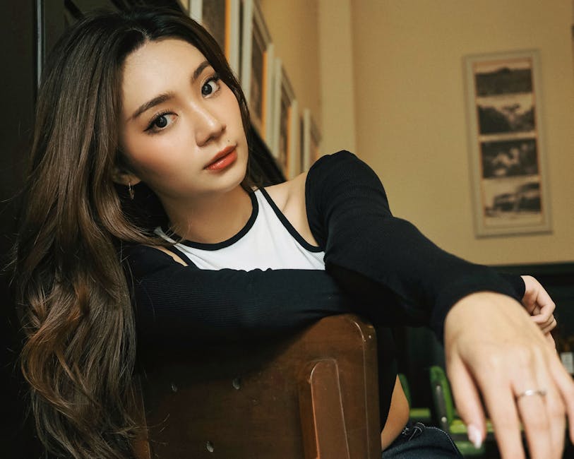 Portrait of a stylish young woman with long hair sitting indoors with a thoughtful expression.