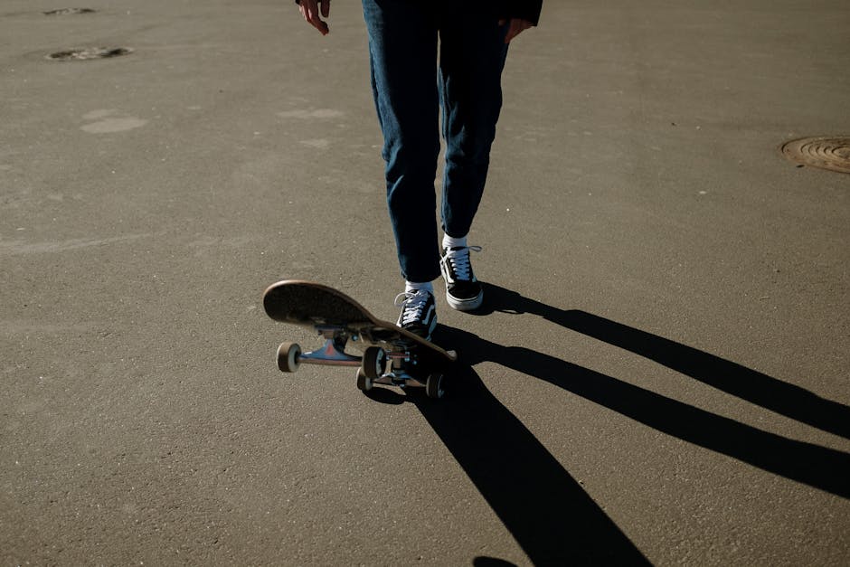 Skateboarder in motion casting a shadow on sunny urban pavement.